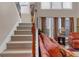 Carpeted staircase with wooden handrail leads upstairs, complemented by nearby windows and an orange sofa at 3919 Teal Cir, Powder Springs, GA 30127