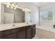 Bright bathroom featuring a double vanity, soaking tub, and large mirror with modern lighting fixtures at 3211 Blaisdell Rd, Buford, GA 30519