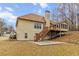Back exterior featuring a deck, sunroom, large yard, and mature trees at 3211 Blaisdell Rd, Buford, GA 30519