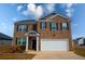 Two-story brick home featuring an attached two-car garage and manicured landscaping at 443 Faulkner St, Stockbridge, GA 30281
