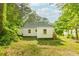 View of a home's back exterior and spacious backyard surrounded by mature trees, a garden, and fence at 451 Collier Ridge Dr, Atlanta, GA 30318