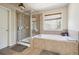 Bathroom featuring a shower with glass door and a soaking tub by a window at 1595 Johnstown Trace, Suwanee, GA 30024