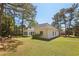 Back view of home with lush green lawn and swing and lots of mature trees at 3100 Plantation Run Dr, Loganville, GA 30052