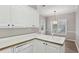 Bright kitchen featuring white cabinets and a double sink with light wood-look floors at 3100 Plantation Run Dr, Loganville, GA 30052
