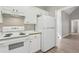 Kitchen featuring white cabinets, white appliances, neutral walls, and light wood-look floors at 3100 Plantation Run Dr, Loganville, GA 30052