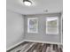 Bright bedroom featuring gray-toned wood floors and two windows at 10540 Willow View Cir, Alpharetta, GA 30022