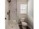 Bathroom showcasing a tiled shower with a black shower head, small window, and modern toilet at 2562 Tritt Springs Ne Trce, Marietta, GA 30062
