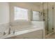 Luxurious bathroom featuring a soaking tub, separate glass-enclosed shower, and marble tile for a spa-like experience at 4565 Sims Park Overlook, Suwanee, GA 30024