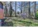 Backyard featuring an overgrown lawn, a greenhouse, mature trees, and lawn furniture at 3007 Pasadena Dr, Decatur, GA 30032
