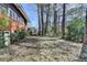 Backyard featuring an overgrown lawn, a brick foundation, and mature trees at 3007 Pasadena Dr, Decatur, GA 30032