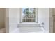 Bathroom featuring a soaking tub under a window and marble accent walls at 3061 Stone Bridge Sw Trl, Conyers, GA 30094