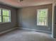 Well-lit bedroom featuring two large windows with scenic views, neutral walls, and hardwood flooring at 6841 Phillips Mill Rd, Douglasville, GA 30135