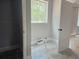 Well-lit laundry room featuring gray tile floors, utility connections, and a window offering natural light at 6841 Phillips Mill Rd, Douglasville, GA 30135