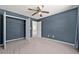 Bedroom features gray carpet, closet, ceiling fan, and blue accent wall at 1358 Mckinsey Rdg, Loganville, GA 30052