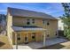 Rear view of two-story home with covered patio and well-maintained lawn at 3483 Summerlin Pkwy, Lithia Springs, GA 30122