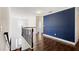 Second-floor hallway with wood floors, blue accent wall, and staircase with rod iron spindles at 3483 Summerlin Pkwy, Lithia Springs, GA 30122