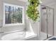 Bright bathroom featuring a soaking tub, a separate glass shower, and a large window with a leafy plant at 2099 Easterwood Ter, Decatur, GA 30032