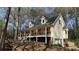 Side view of a two-story home with a stone foundation, a front porch, and lots of landscaping at 705 Mill Creek Rdg, Woodstock, GA 30188