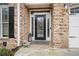 Close-up of a brick home's front entrance with decorative glass door, sidelights, and a stone landing with a cute bulldog statue at 1525 Camden Cove Dr, Cumming, GA 30040