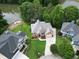 Aerial view of a lakeside home featuring a spacious driveway, lush landscaping, and private dock at 335 Lake Bluff Ct, Suwanee, GA 30024
