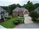 Two-story brick home featuring a spacious driveway, lush landscaping, and 'For Sale' sign at 335 Lake Bluff Ct, Suwanee, GA 30024