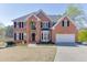 Charming brick two-story home with black shutters, attached garage, and lakeside view at 335 Lake Bluff Ct, Suwanee, GA 30024