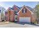 Brick home with a large arched entryway and a well-maintained lawn and garden at 335 Lake Bluff Ct, Suwanee, GA 30024