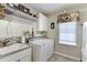 Clean laundry room featuring a washer, dryer, utility sink, and storage shelves at 335 Lake Bluff Ct, Suwanee, GA 30024