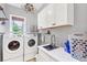 Bright laundry room features modern washer and dryer, wash basin, and storage for functional convenience at 4020 Toulon Ln, Cumming, GA 30040