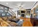Cozy living room with a stone fireplace, built-in shelving, ceiling fan and staircase at 4020 Toulon Ln, Cumming, GA 30040