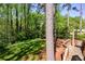 View of spacious backyard with lush lawn and tall trees from wooden deck at 4400 Huntington Cir, Dunwoody, GA 30338
