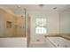 Luxurious bathroom featuring tiled walk-in shower, a large window, and a soaking tub at 4400 Huntington Cir, Dunwoody, GA 30338
