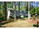 View of the home with blue siding and stone accents nestled among lush trees and greenery at 4400 Huntington Cir, Dunwoody, GA 30338