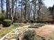 Landscaped backyard featuring stone pathways, garden beds, and mature trees at 509 Carrington Ct, Canton, GA 30115