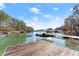 Scenic lake view from the dock showcasing calm water, covered boat slips, and clear blue skies, surrounded by trees at 2655 Lakeside Trl, Cumming, GA 30041