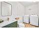 Bright laundry room with a green vanity, modern mirror and new, white front load washer and dryer at 6828 Lockridge Dr, Atlanta, GA 30360