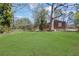 Large, grassy backyard featuring mature trees and a brick house, perfect for outdoor activities at 1883 Clarke Ln, Decatur, GA 30035