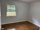 This bedroom features hardwood floors, neutral paint and a sunny window overlooking the neighborhood at 877 Verona Dr, Clarkston, GA 30021