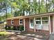 Charming brick home featuring a cozy front porch, manicured landscaping, and surrounded by mature trees at 877 Verona Dr, Clarkston, GA 30021