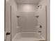 Well-lit tub and shower area in the bathroom features tiled walls and built-in shelves at 1659 Hay Patch Ln, Loganville, GA 30052