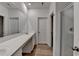 Bright bathroom with dual sinks, a large mirror, wood flooring, and glass enclosed shower at 1659 Hay Patch Ln, Loganville, GA 30052