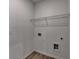 Laundry room with white walls and wood look floor, featuring hook ups and shelving at 1659 Hay Patch Ln, Loganville, GA 30052