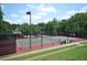 Well-maintained tennis court with lighting surrounded by lush greenery in the Legacy Park community at 3820 Mast Nw Ct, Kennesaw, GA 30144