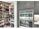 Well-organized pantry with custom shelving, alongside a built-in stainless steel oven and gray kitchen cabinets at 1007 Belle Ave, Roswell, GA 30076