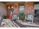 Cozy front porch with rocking chairs, vibrant red door, and charming brick accents at 3123 Neal Ct, Cumming, GA 30041