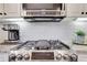Close-up view of the stainless steel gas cooktop and stylish tile backsplash in this well-appointed modern kitchen at 3123 Neal Ct, Cumming, GA 30041