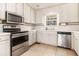 A well-lit kitchen equipped with stainless steel appliances, white cabinets, and tile flooring at 170 Double D Rd, Temple, GA 30179