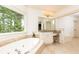 Luxurious bathroom with a soaking tub by the window, granite counters, and vanity area at 570 Glengate Cv, Atlanta, GA 30328
