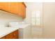 Bright laundry room featuring wooden cabinets, white appliances, and shuttered windows at 570 Glengate Cv, Atlanta, GA 30328