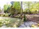 Lush backyard landscaping, featuring flowerbeds, steps, and a path leading through mature trees at 825 Glengate Pl, Atlanta, GA 30328